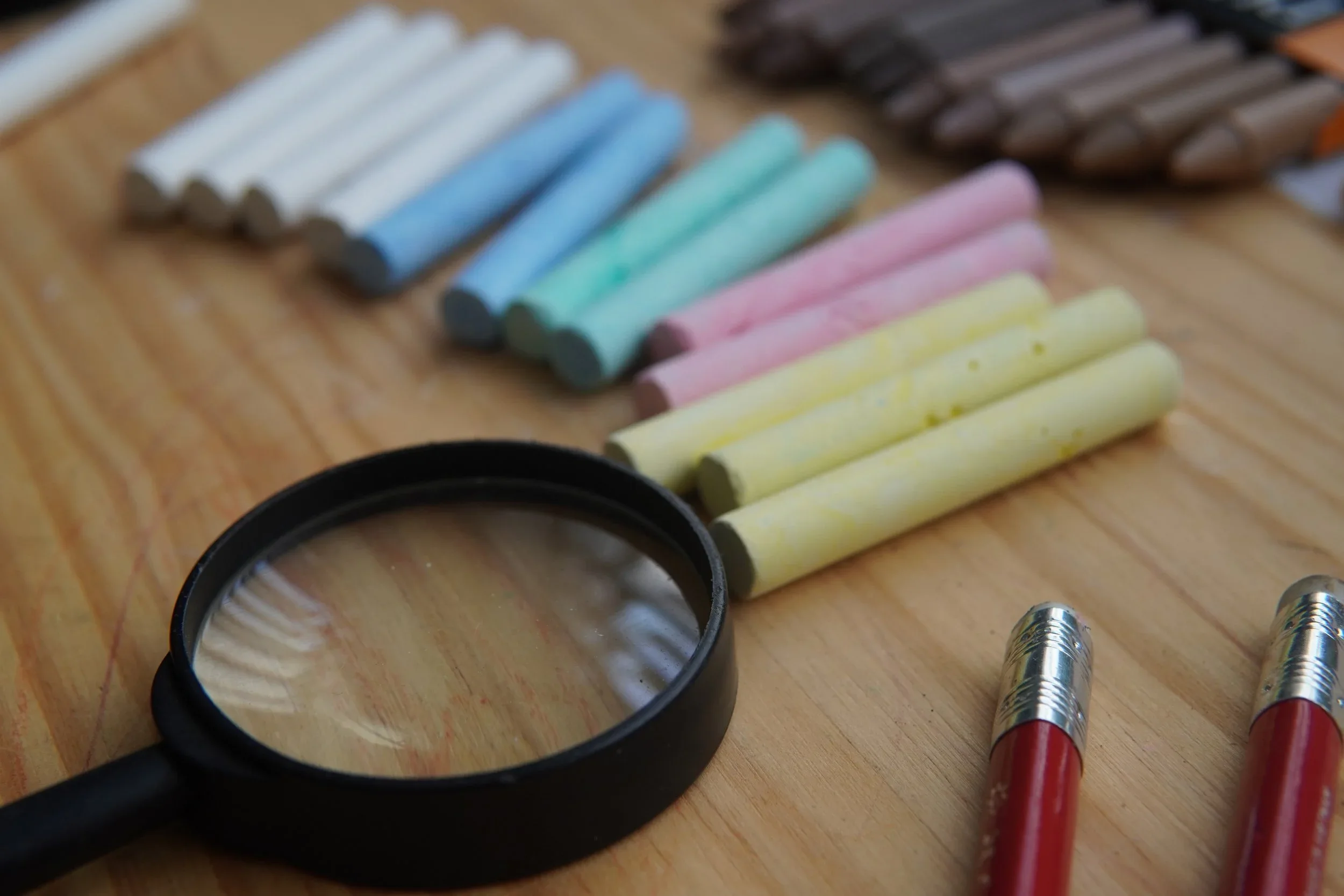 Gizes coloridos e lupa sobre a mesa