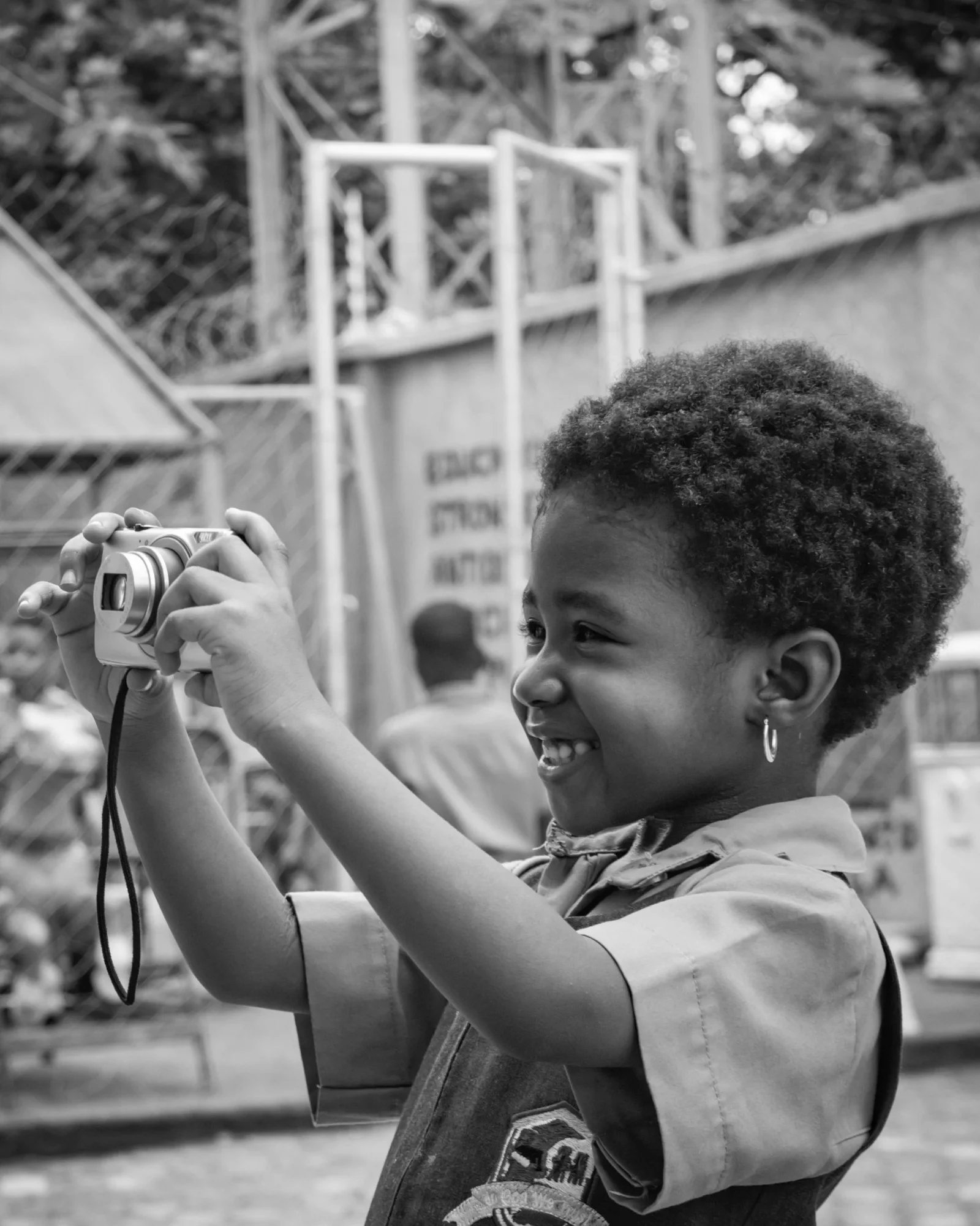 Criança sorrindo enquanto fotografa com uma câmera